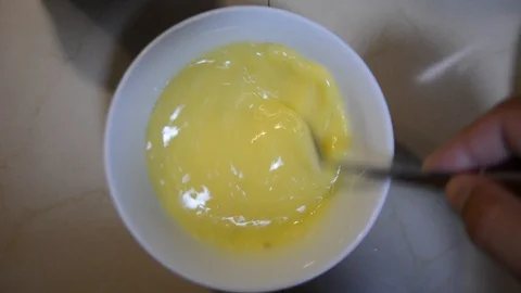 The hand whips with a fork chicken eggs in a bowl in the kitchen to make an omel Stock Footage 118671370