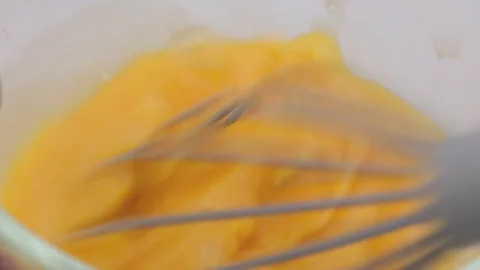 Hand whisking eggs. Beating chicken eggs in glass bowl with manual mixer Stock Footage 248435482