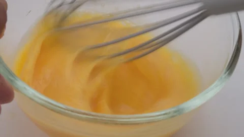 Hand whisking eggs. Beating chicken eggs in glass bowl with manual mixer Stock Footage 248435486