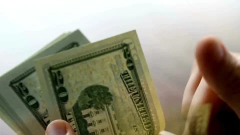 Hand on white background holds bundle of one hundred dollar bills, American.. Stock Footage 266475732