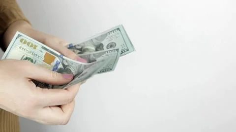 Hand on white background holds bundle of one hundred dollar bills, American 스톡 동영상 336264060