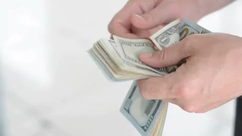 Hand on white background holds bundle of one hundred dollar bills, American 스톡 동영상 336264506