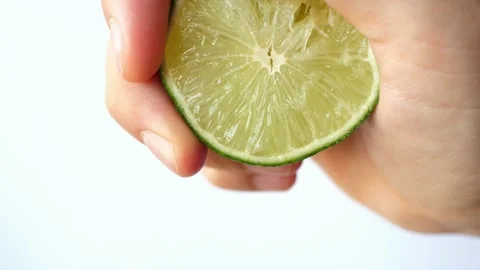 Hand on white background squeezes squeezing juice of half a lime Stock Footage 133559913