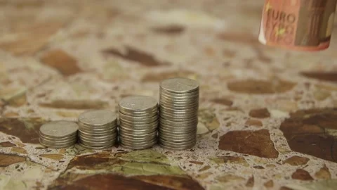 A hand in a white glove puts rolled 10 euro banknotes next to stacks of coins Vídeos de archivo 142505997