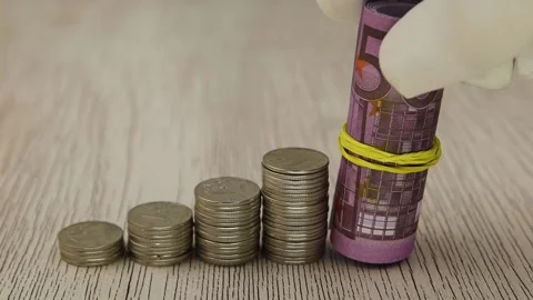 A hand in a white glove puts rolled 500 euro banknotes next to stacks of coins Vídeo Stock 143084071