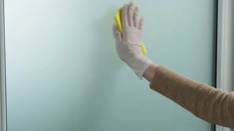 Hand in white gloves cleaning window with yellow rag and cleanser spray at home Stock Footage 130882653