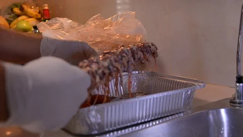 Hand in white gloves puts pieces of marinated chicken on the grill Stock Footage 81650807