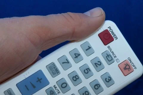 Hand with a white remote control with multi-colored buttons Foto stock