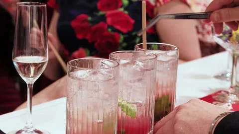 The hand of a white-skinned man mixes an alcoholic cocktail with ice with a card Stock Footage 156612239