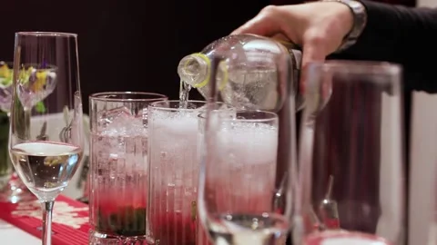 The hand of a white-skinned man pours a carbonated drink into a glass with ice.  Stock Footage 156612221