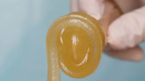 Hand in white surgical glove is rolling sugar paste for depilation Видео 169998939