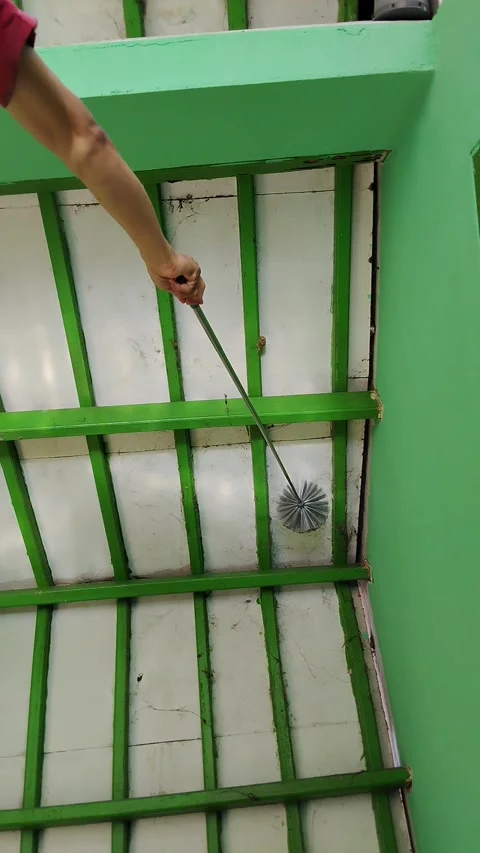 Hand wields long-handled brush against green-rimmed tile wall Видео 330644611