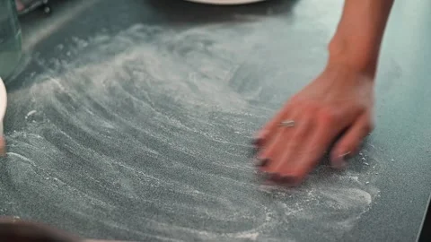 A hand wipes flour off a kitchen counter in a clean and bright cooking area. Video stock 339095782