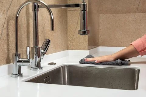 Hand wipes the surface of the table in the kitchen with a dry rag Stock Photos