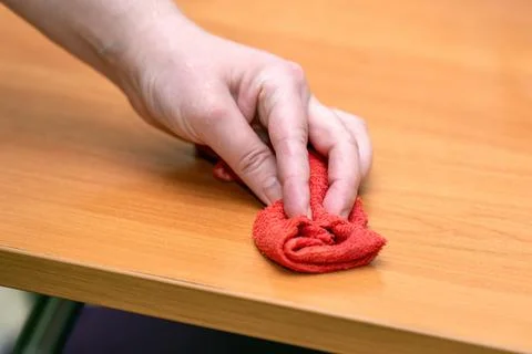 Hand wipes a table with a red microfiber cloth, showcasing effective cleaning Stock Photos