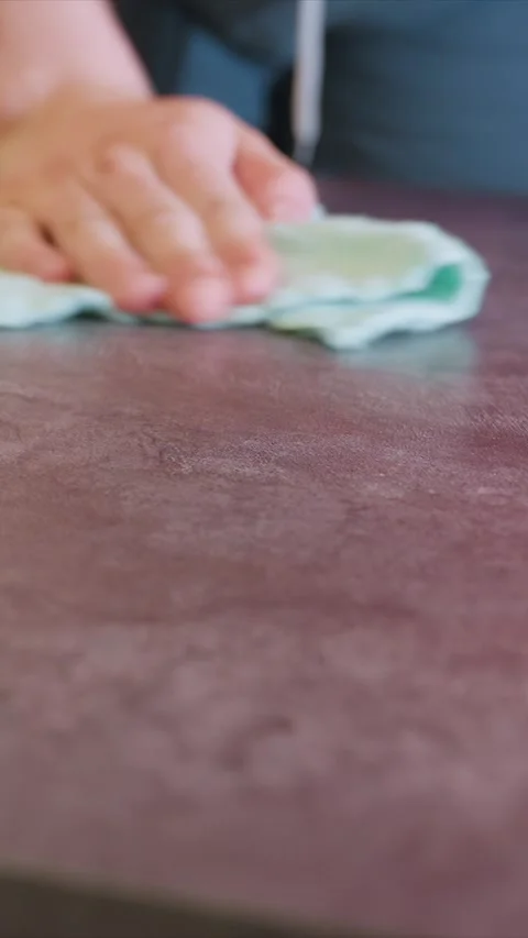 Hand Wiping Maroon Surface Close up with cloth table countertop cleaning texture Stock Footage 346787904