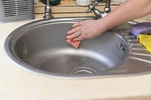 Hand wiping sink using sponge, hand removing dirt from stainless steel basin, Stock Photos