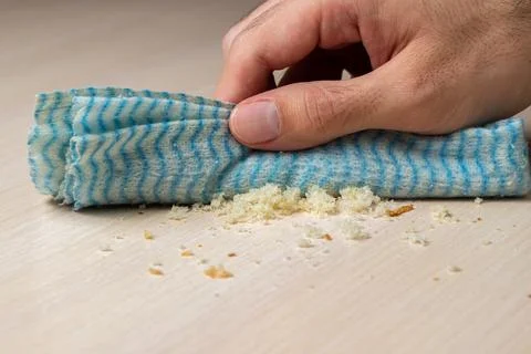 The hand is wiping the table with a rag. Stock Photos