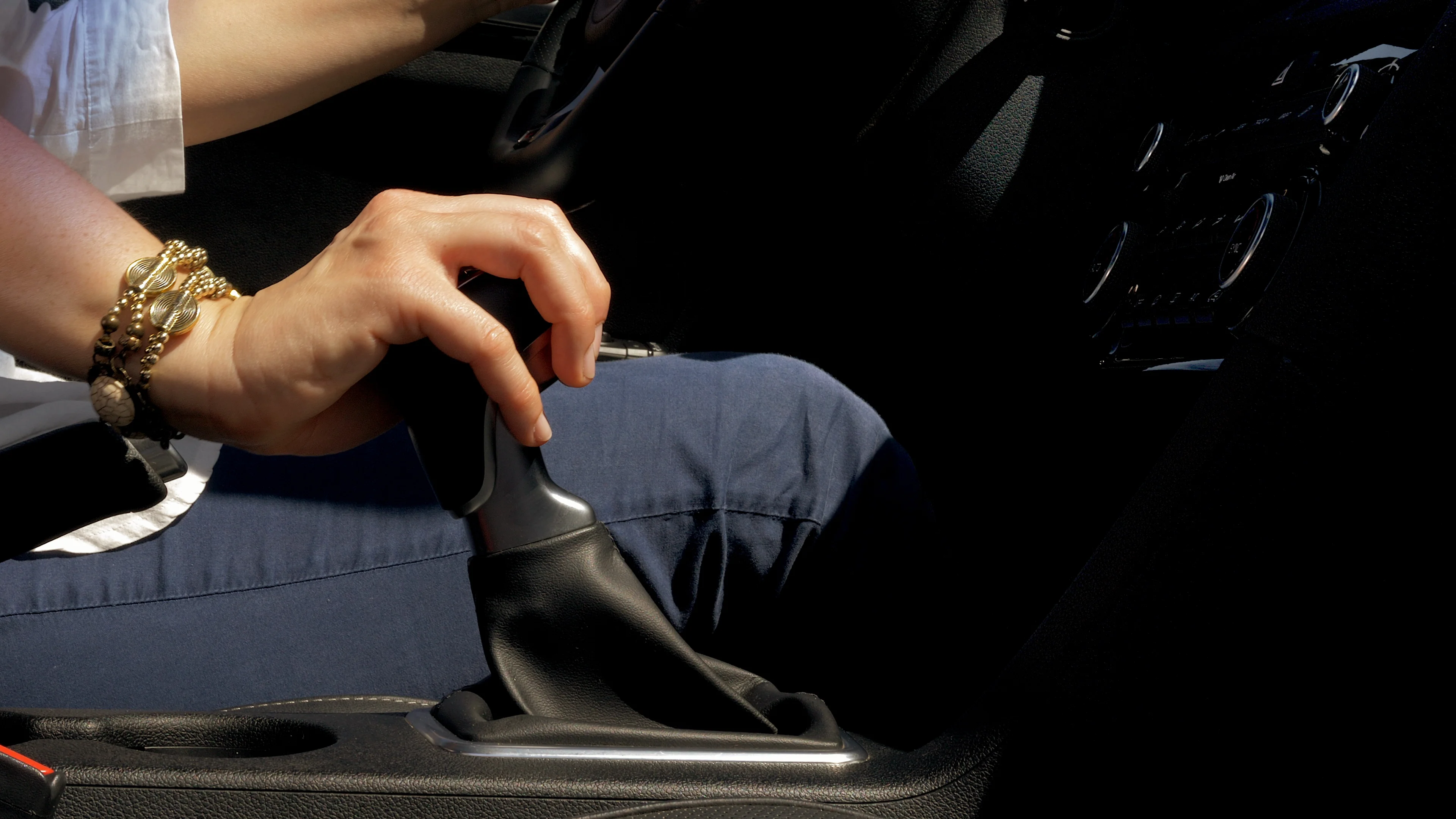 Hand of woman changing gear while driving car at sunset