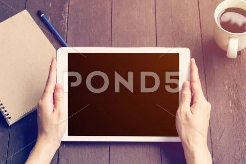 Hand woman holding tablet workink on wood table in coffee shop with vintage f Stock Photos