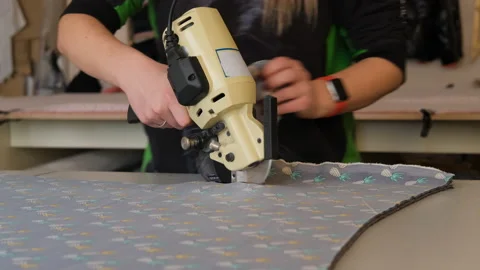 Hand of Woman Using Machine for Cutting Fabrics Stock Footage 150932389