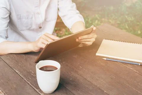 Hand woman using tablet on table in garden at coffee shop with vintage toned. Stock Photos