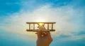 The hand with a wooden plane on the background of the bright sun Photo