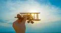 The hand with a wooden plane on the background of the sunrise Photo