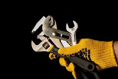The hand in a work glove of the master holds a set of tools Stock Photos