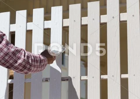 Hand worker holding brush painting white on wood fence Stock Photos