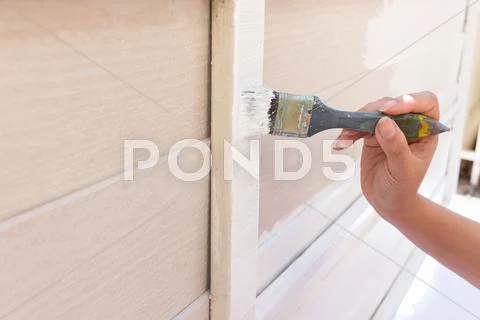 Hand worker holding brush painting white on wood fence Stock Photos