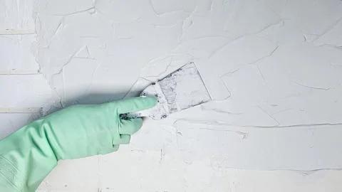 The hand of a worker holding a spatula for applying putty to the walls Stock Photos