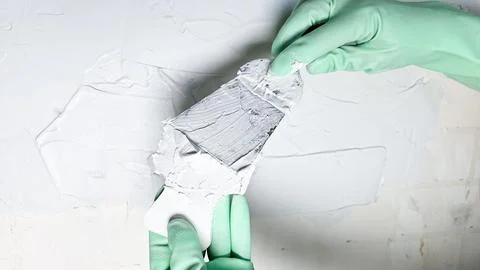 The hand of a worker holding a spatula for applying putty to the walls Stock Photos