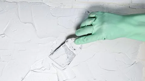 The hand of a worker holding a spatula for applying putty to the walls Stock Photos