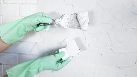 The hand of a worker holding a spatula for applying putty to the walls Stock Photos