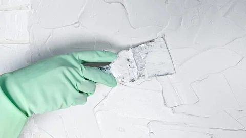 The hand of a worker holding a spatula for applying putty to the walls Stock Photos