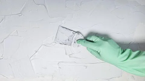 The hand of a worker holding a spatula for applying putty to the walls Stock Photos