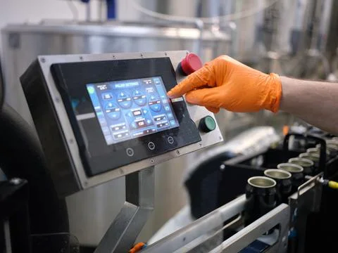 Hand of a worker touching the screen of an electronic machine of a brewery Stock Photos