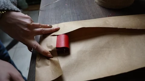 Hand Wrapping Red Leather Wallet in Kraft Paper Stock Footage 315529216