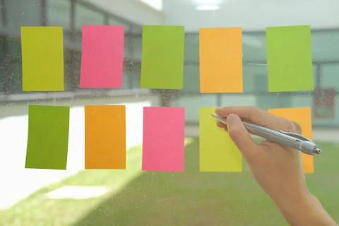 Hand write on adhesive notes on glass wall. Sticky note paper reminder schedu Stock-Fotos
