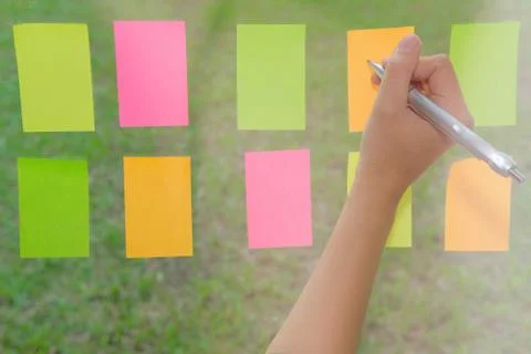 Hand write on adhesive notes on glass wall. Sticky note paper reminder schedu Stock Photos
