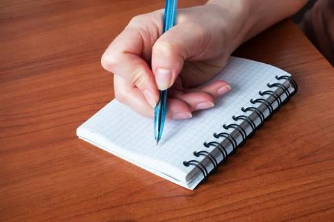 Hand write on notebook. Close up. Wooden table. Stock-Fotos