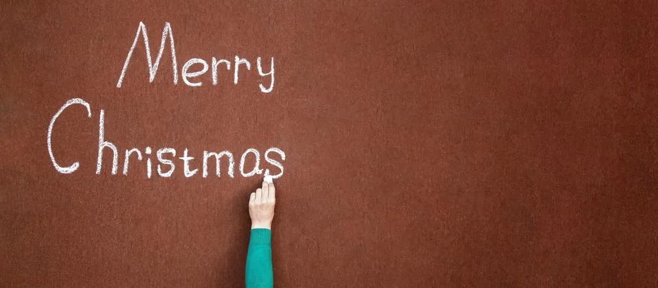 Hand writes with chalk on an abstract surface Merry Christmas, written in c.. Stock Photos