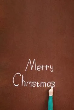 Hand writes with chalk on an abstract surface Merry Christmas, written in c.. Stock Photos