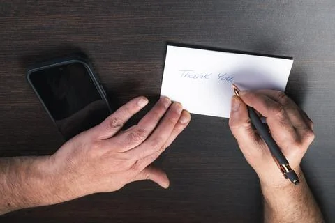 Hand writes heartfelt note on white card Stock Photos