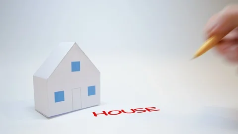 Hand writes house writing next to a paper house Stock Footage 98976323