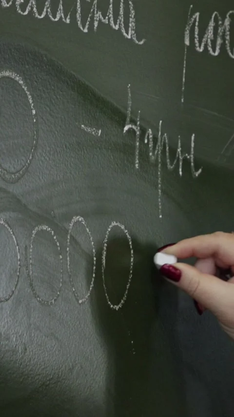 A hand writes math numbers with white chalk on a green classroom blackboard.. Stock Footage 339861180