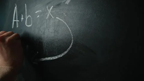 A hand writes mathematical equations on a chalkboard while attempting to solve a 動画素材 338186462