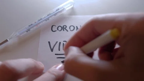 A hand writes on a note the word Corona Virus thermometer Stock Footage 125222212