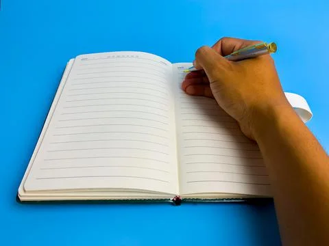 Hand writes in a notebook on a blue background Stock Photos